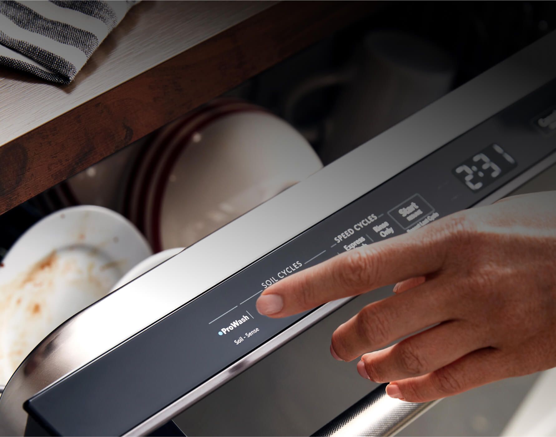 A hand closes the dishwasher — showing us the hidden controls, digital clock and the iconic KitchenAid handle.